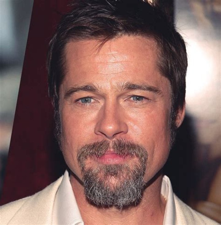 a man with a goatee and beard wearing a leather jacket looking at the